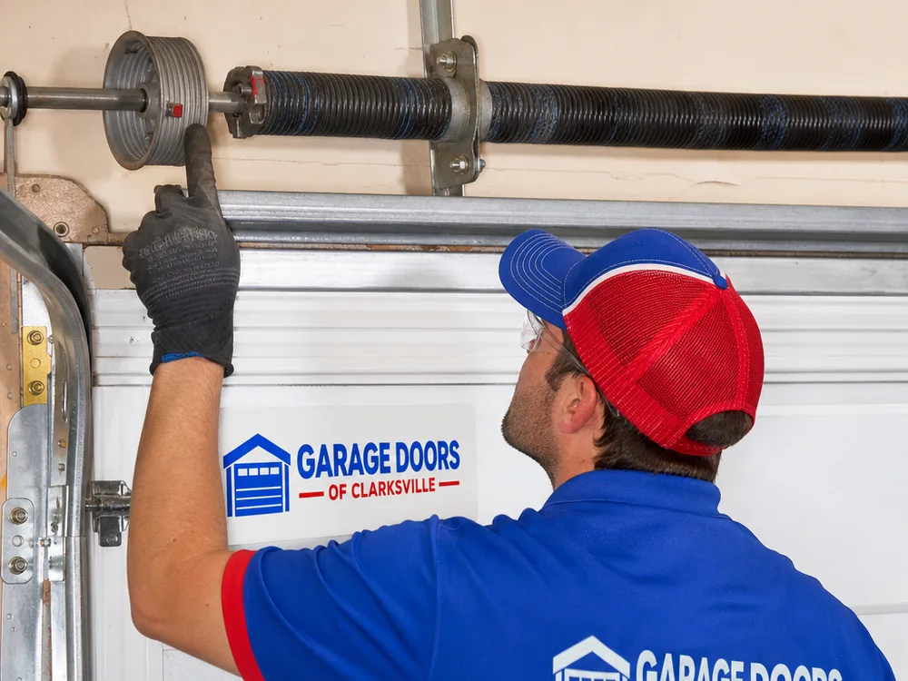 Garage door torsion spring and center bearing plate with gloved hands indicating a worn cable drum
